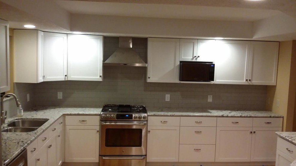 Mid-sized transitional l-shaped medium tone wood floor open concept kitchen photo with a double-bowl sink, shaker cabinets, white cabinets, granite countertops, gray backsplash, subway tile backsplash, stainless steel appliances and an island