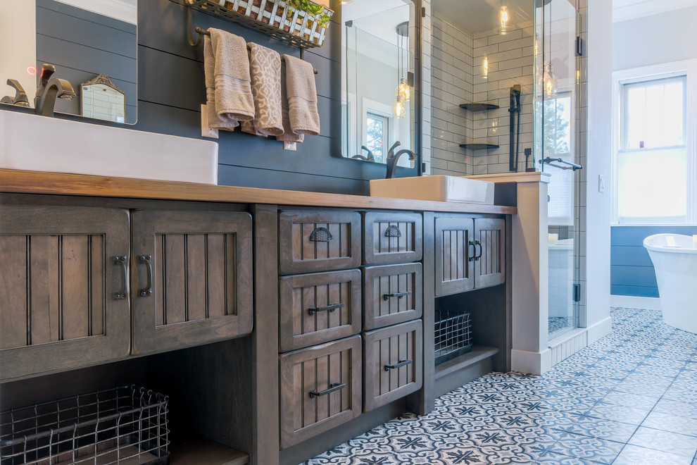 Design ideas for a mid-sized country master bathroom in Detroit with recessed-panel cabinets, brown cabinets, a freestanding tub, a corner shower, blue walls, mosaic tile floors, a vessel sink, wood benchtops, blue floor, a hinged shower door and brown benchtops.