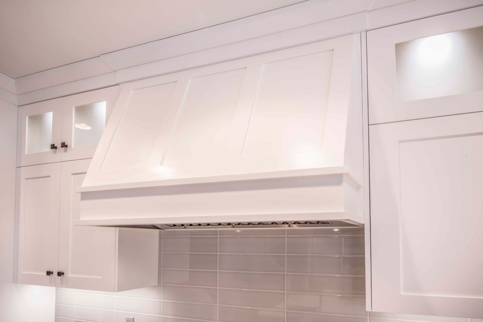 Mid-sized transitional u-shaped medium tone wood floor and brown floor home design photo in Calgary with an undermount sink, flat-panel cabinets, white cabinets, marble countertops, gray backsplash, ceramic backsplash, paneled appliances and an island
