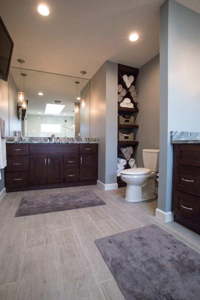 Inspiration for a large traditional master bathroom in Cleveland with an undermount sink, shaker cabinets, dark wood cabinets, granite benchtops, a double shower, a two-piece toilet, gray tile, porcelain tile, grey walls and porcelain floors.