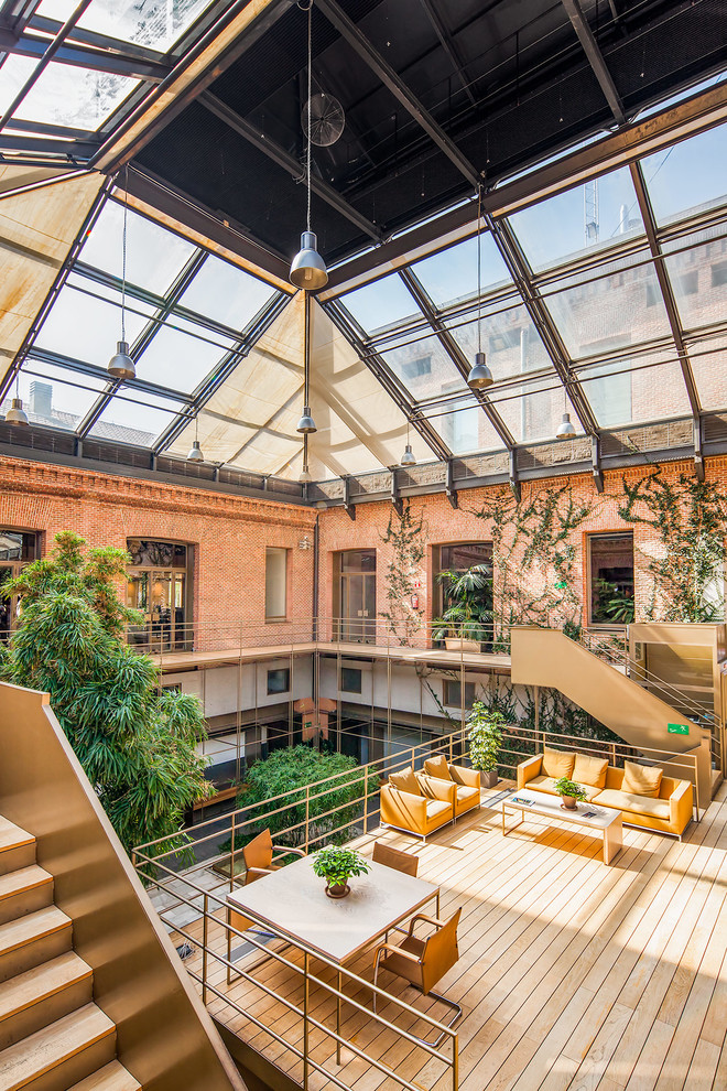Inspiration for an expansive industrial sunroom in Madrid with medium hardwood floors, no fireplace and a skylight.