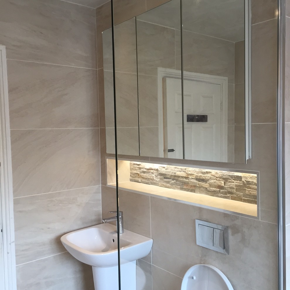 Inspiration for a mid-sized contemporary kids bathroom in Dublin with glass-front cabinets, white cabinets, a freestanding tub, an open shower, a wall-mount toilet, beige tile, ceramic tile, beige walls, ceramic floors, a wall-mount sink and tile benchtops.