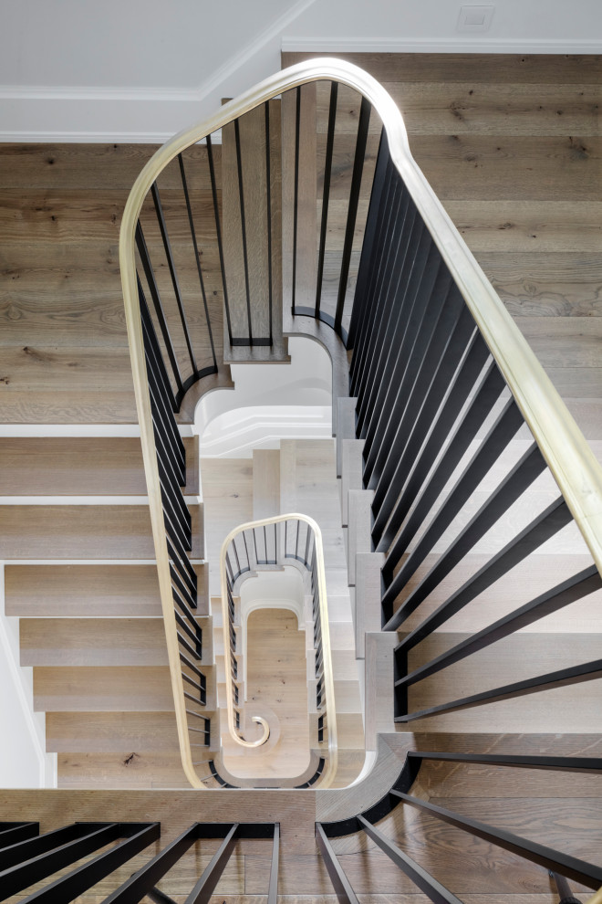 Example of a large classic wooden spiral metal railing and wainscoting staircase design in Boston with wooden risers