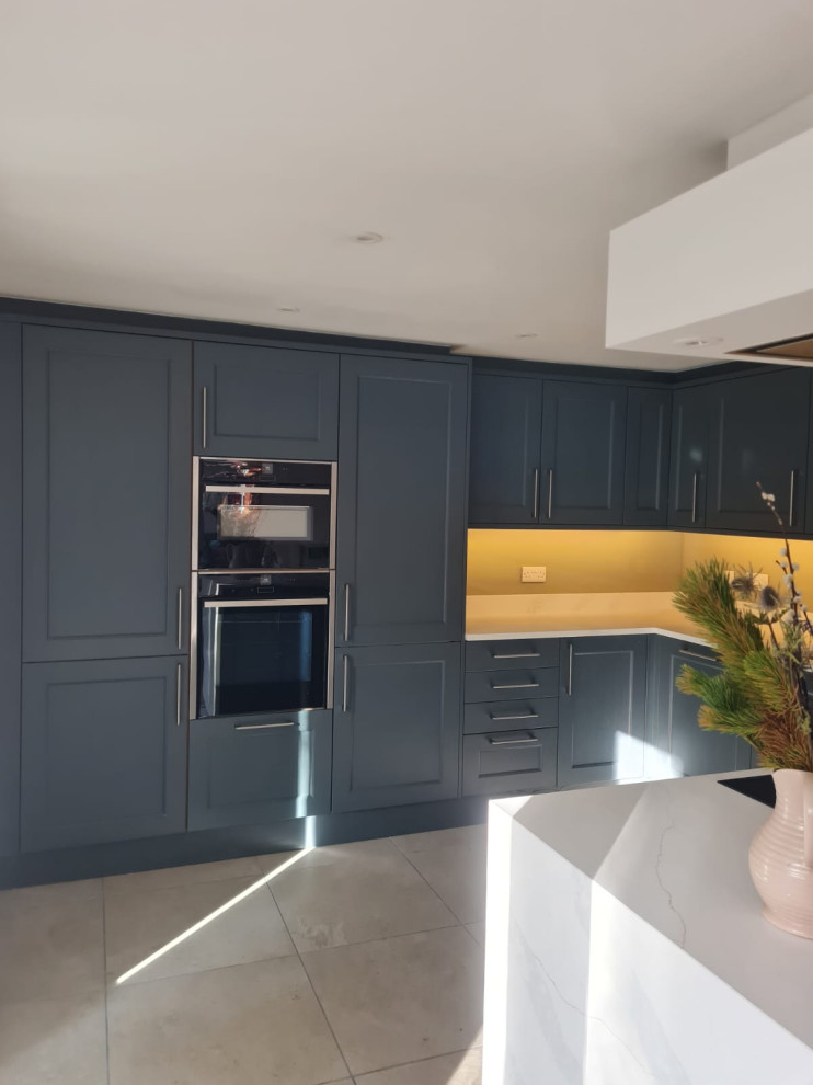 Medium sized contemporary grey and white u-shaped open plan kitchen in Edinburgh with a submerged sink, shaker cabinets, grey cabinets, quartz worktops, engineered quartz splashback, black appliances, ceramic flooring, multi-coloured floors, white worktops, a drop ceiling and feature lighting.