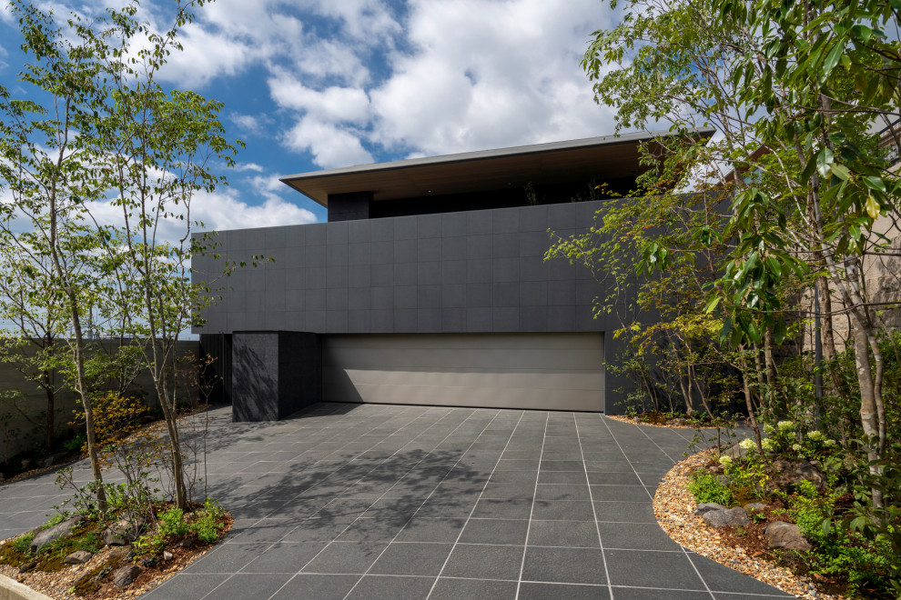 Idée de décoration pour une très grande façade de maison noire minimaliste en pierre à un étage avec un toit à quatre pans, un toit en métal et un toit gris.