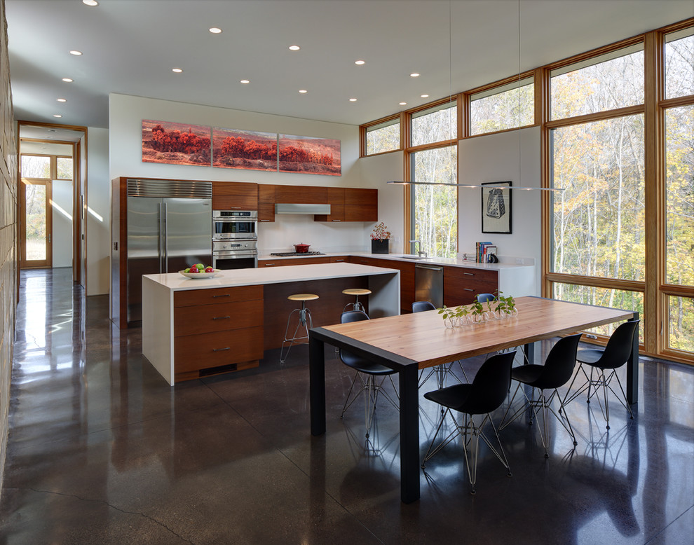 This is an example of a mid-sized contemporary l-shaped open plan kitchen in Milwaukee with flat-panel cabinets, medium wood cabinets, stainless steel appliances, concrete floors, an undermount sink, with island and brown floor.