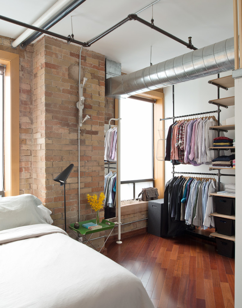 Photo of a mid-sized industrial master bedroom in Toronto with white walls, medium hardwood floors, no fireplace and brown floor.