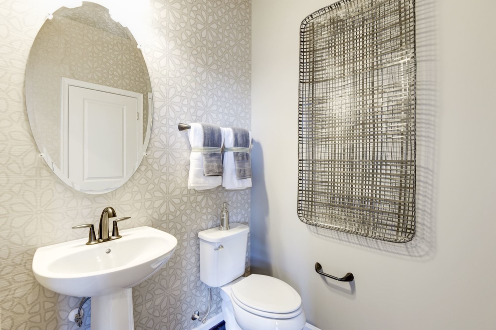 Photo of a mid-sized transitional powder room in DC Metro with a two-piece toilet, beige tile, beige walls, dark hardwood floors, a pedestal sink and brown floor.