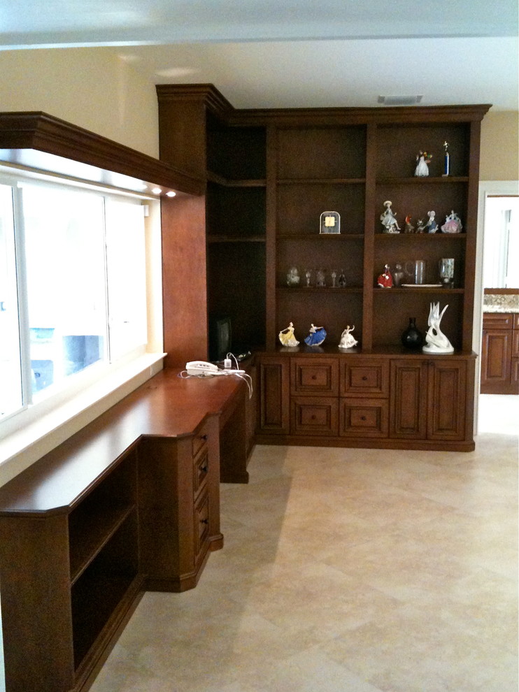 This is an example of a mid-sized traditional home office in Miami with a library, brown walls, travertine floors, a built-in desk and beige floor.