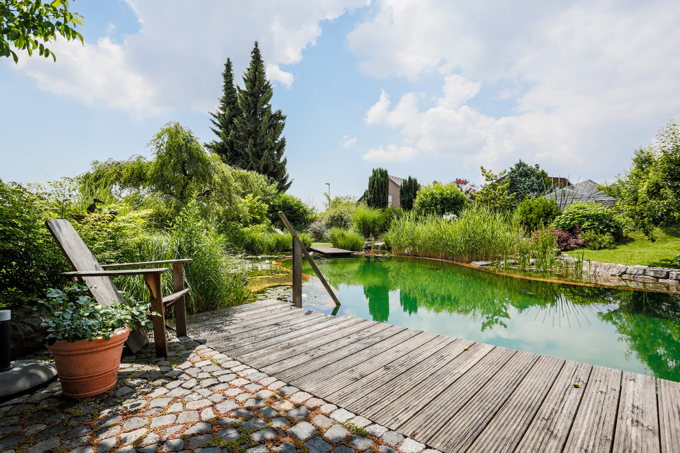 Inspiration for a large country custom-shaped natural pool in Stuttgart with decking.