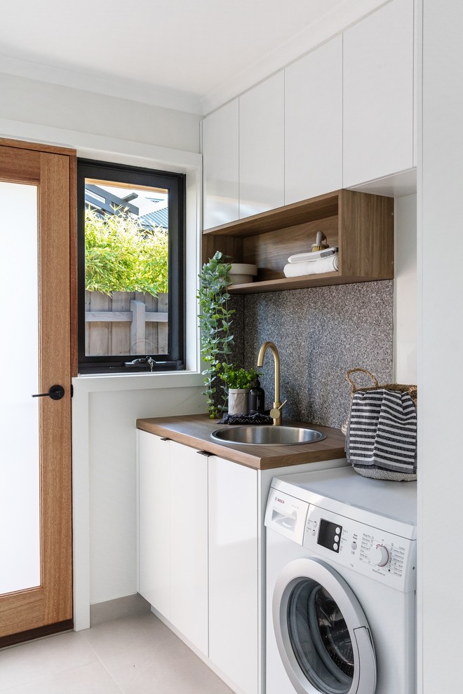 This is an example of a small modern single-wall laundry room in Melbourne with open cabinets and yellow walls.