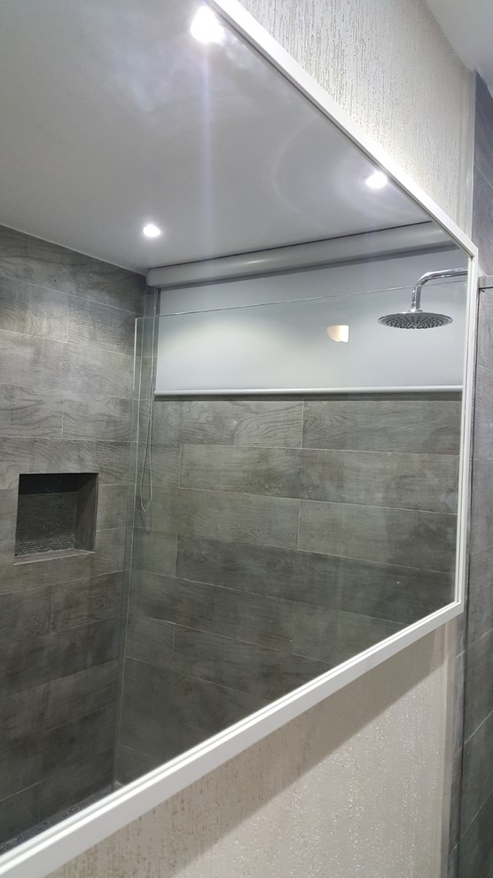 Photo of a small modern bathroom in Other with grey cabinets, an open shower, a one-piece toilet, gray tile, porcelain tile, white walls, ceramic floors, an integrated sink and quartzite benchtops.