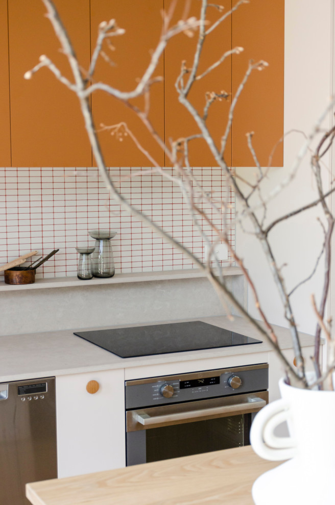 Пример оригинального дизайна: параллельная кухня среднего размера в стиле модернизм с обеденным столом, врезной мойкой, плоскими фасадами, оранжевыми фасадами, деревянной столешницей, белым фартуком, фартуком из плитки мозаики, техникой из нержавеющей стали, полом из ламината, островом, желтым полом и желтой столешницей