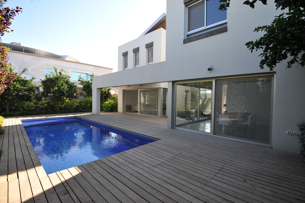 Modern backyard rectangular pool in Other with decking.