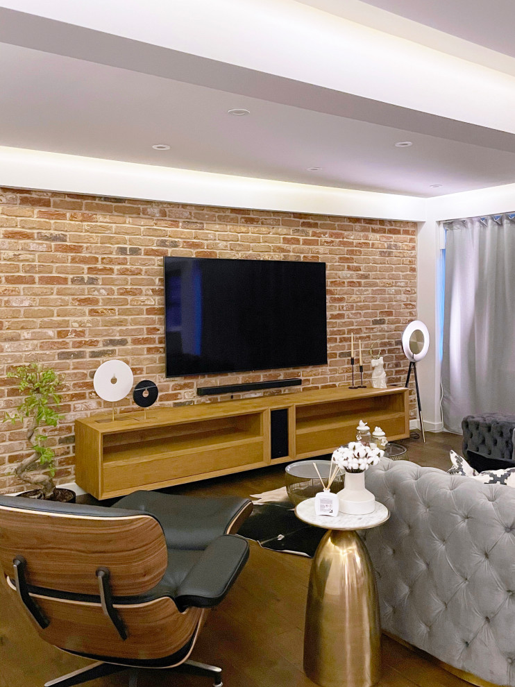 Inspiration for a mid-sized modern open concept living room in New York with light hardwood floors, a wall-mounted tv, brick walls, no fireplace, brown floor and white walls.