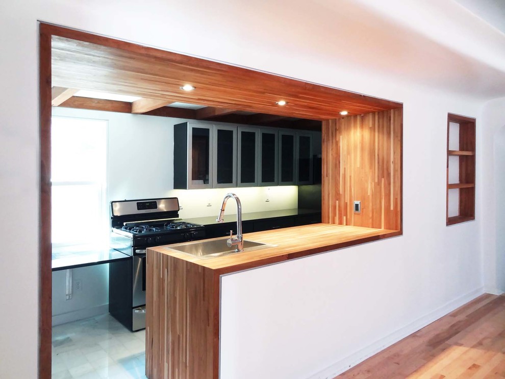 Mid-sized contemporary galley separate kitchen in New York with a drop-in sink, glass-front cabinets, grey cabinets, wood benchtops, white splashback, stone slab splashback, stainless steel appliances, marble floors, a peninsula and white floor.