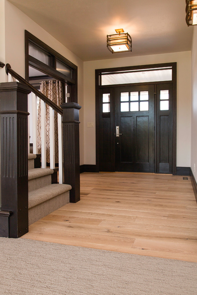 Example of a mid-sized arts and crafts light wood floor and brown floor front door design with beige walls and a dark wood front door