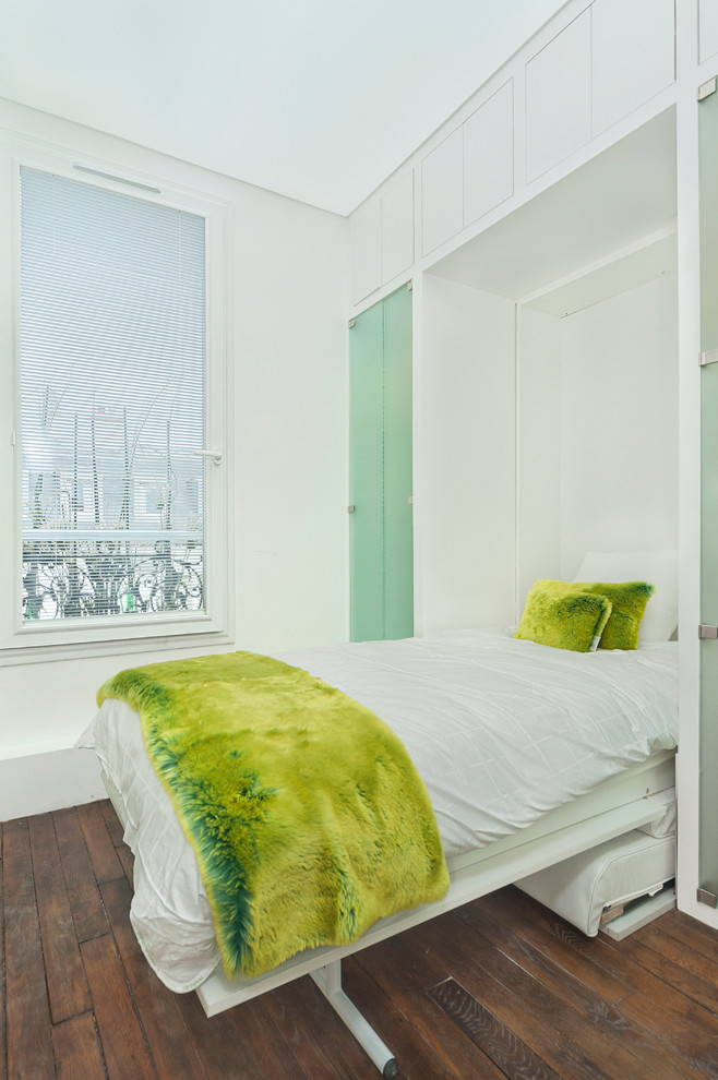 Mid-sized master bedroom in Paris with white walls and medium hardwood floors.