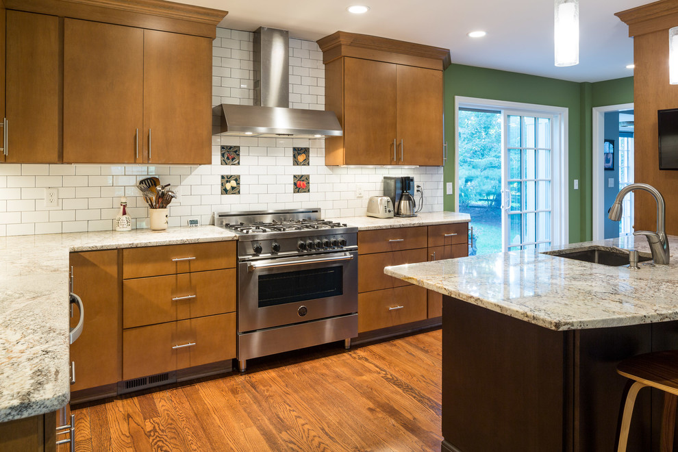 Photo of a mid-sized modern l-shaped eat-in kitchen in Cincinnati with a drop-in sink, flat-panel cabinets, light wood cabinets, white splashback, subway tile splashback, stainless steel appliances, light hardwood floors and with island.