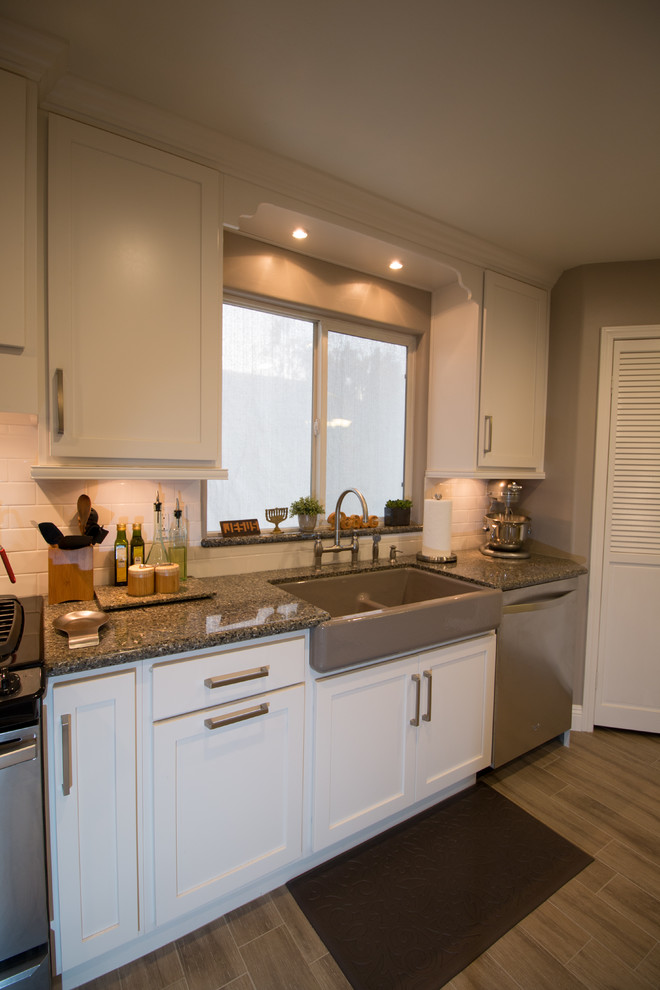 Inspiration for a mid-sized transitional galley porcelain tile open concept kitchen remodel with a farmhouse sink, shaker cabinets, white cabinets, quartz countertops, white backsplash, subway tile backsplash and stainless steel appliances