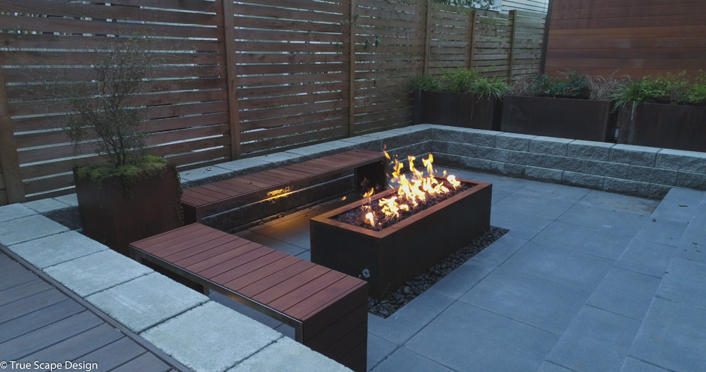 Inspiration for a small modern backyard shaded xeriscape in Seattle with a fire feature and concrete pavers.