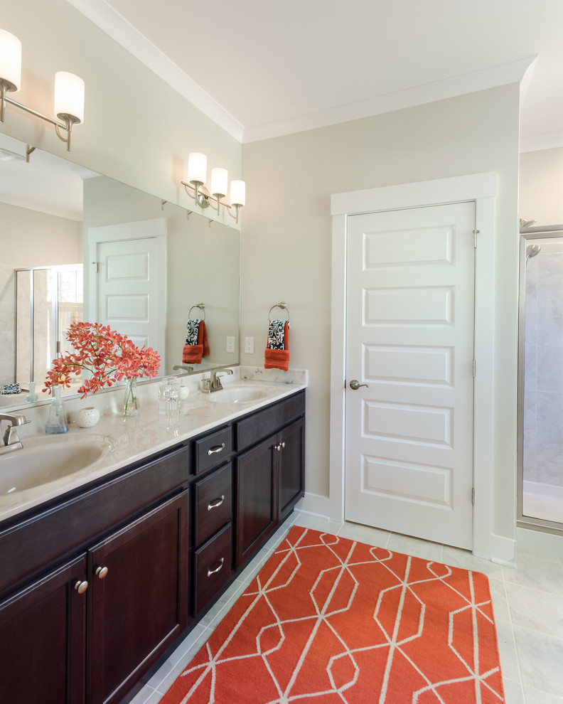 Design ideas for a mid-sized beach style master bathroom in Richmond with recessed-panel cabinets, dark wood cabinets, beige walls, limestone floors, an integrated sink and beige floor.