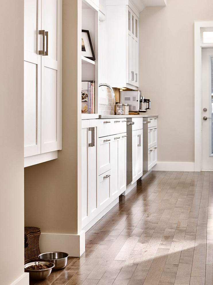 Open concept kitchen - large transitional u-shaped medium tone wood floor open concept kitchen idea with an undermount sink, shaker cabinets, white cabinets, quartz countertops, white backsplash, subway tile backsplash, stainless steel appliances and an island