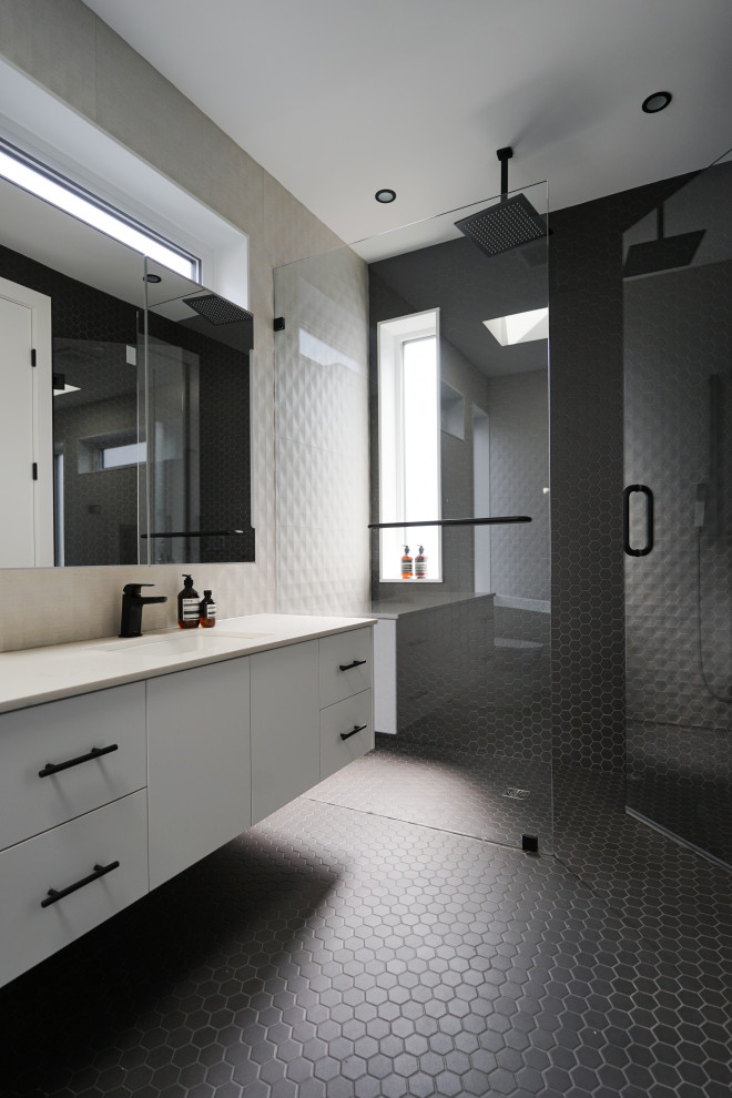 Design ideas for a medium sized modern ensuite bathroom in Vancouver with a freestanding bath, a built-in shower, a one-piece toilet, grey tiles, ceramic tiles, grey walls, ceramic flooring, a vessel sink, quartz worktops, black floors, a hinged door, white worktops, a single sink, a floating vanity unit and a vaulted ceiling.