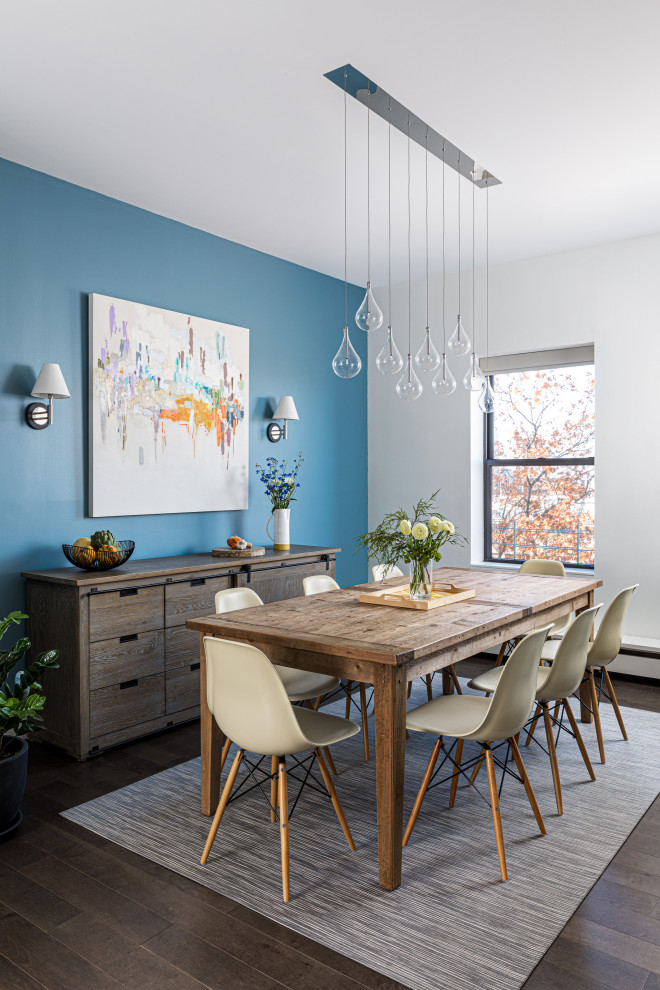 Cette image montre une petite salle à manger ouverte sur le salon design avec un mur bleu, parquet foncé et un sol marron.