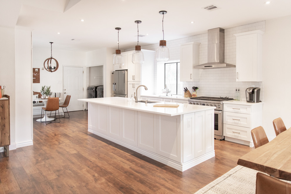 Example of a mid-sized transitional medium tone wood floor and brown floor eat-in kitchen design in Phoenix with shaker cabinets, white cabinets, white backsplash, subway tile backsplash, stainless steel appliances and an island