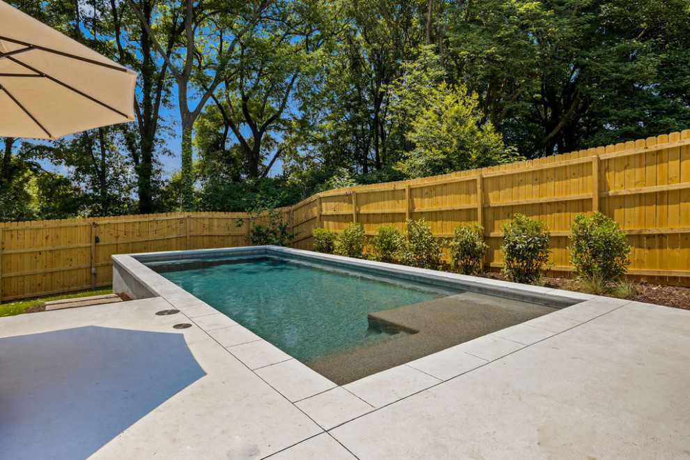 Foto de piscina contemporánea de tamaño medio rectangular en patio trasero con privacidad y suelo de hormigón estampado