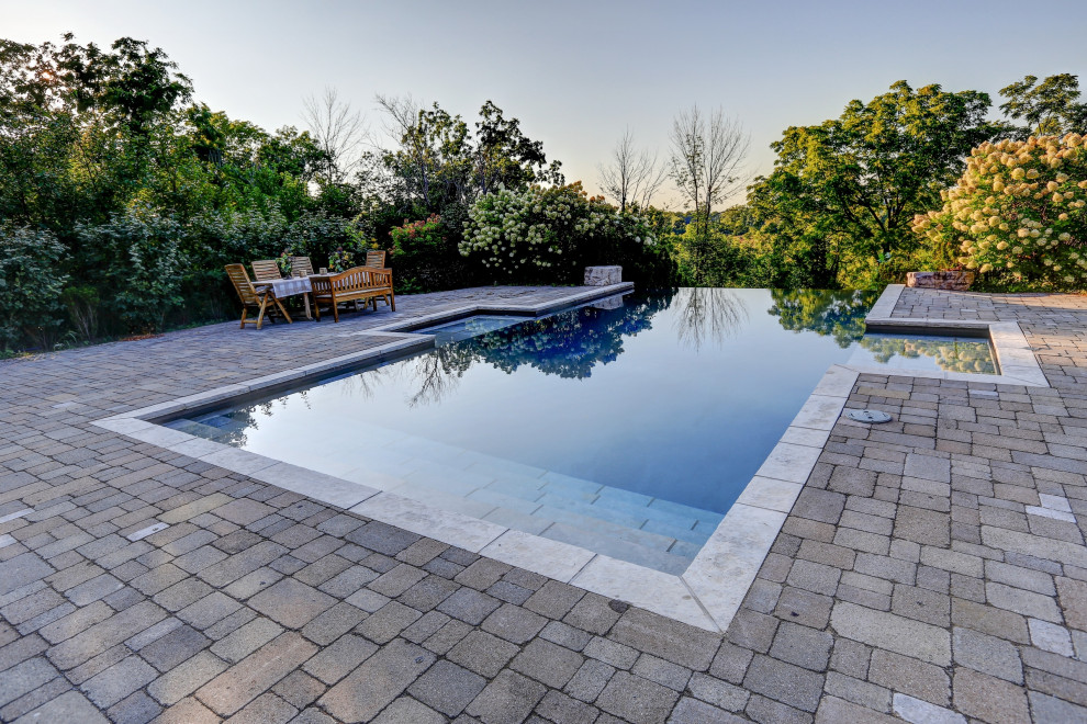 Example of a mid-sized backyard concrete paver and rectangular infinity pool design in Toronto