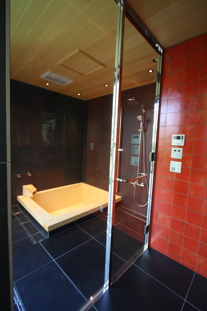 Asian wet room bathroom in Other with a hot tub, black tile, black walls, black floor, a hinged shower door and wood.