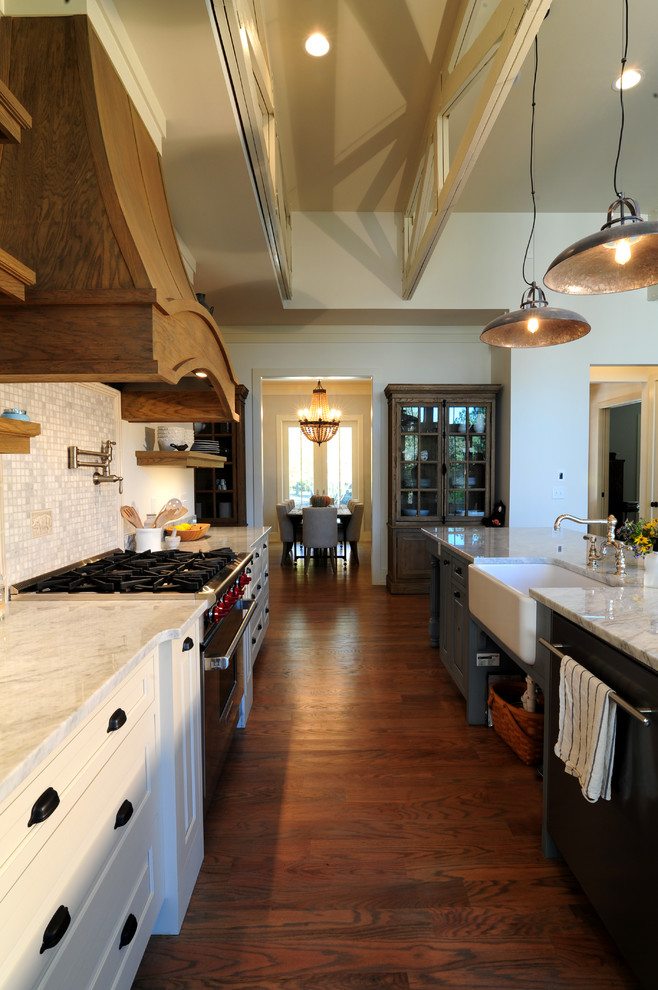 Open concept kitchen - mid-sized craftsman galley medium tone wood floor open concept kitchen idea with a farmhouse sink, raised-panel cabinets, beige cabinets, marble countertops, gray backsplash, stone tile backsplash, stainless steel appliances and an island
