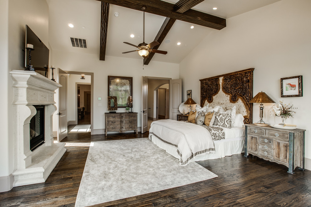 Large mediterranean master bedroom in Dallas with beige walls, medium hardwood floors, a standard fireplace and a stone fireplace surround.