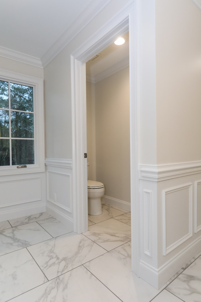 Photo of a large transitional master bathroom in Atlanta with furniture-like cabinets, grey cabinets, a corner shower, a two-piece toilet, gray tile, porcelain tile, white walls, porcelain floors, an undermount sink, engineered quartz benchtops, white floor, a hinged shower door, grey benchtops, an enclosed toilet, a double vanity, a built-in vanity and decorative wall panelling.