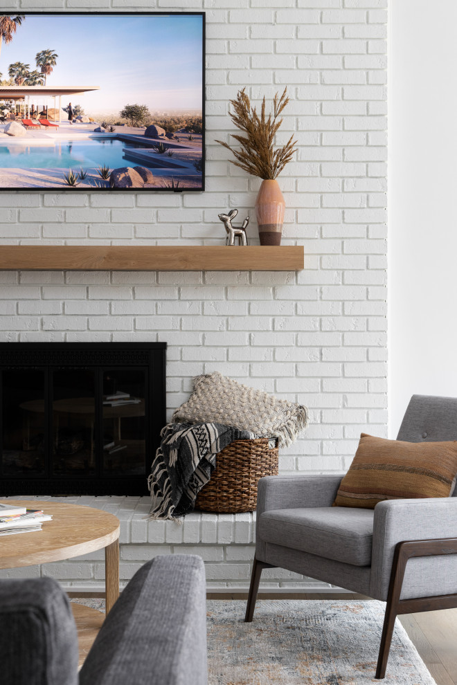 Inspiration för ett stort minimalistiskt allrum med öppen planlösning, med vita väggar, ljust trägolv, en standard öppen spis, en spiselkrans i tegelsten och en väggmonterad TV
