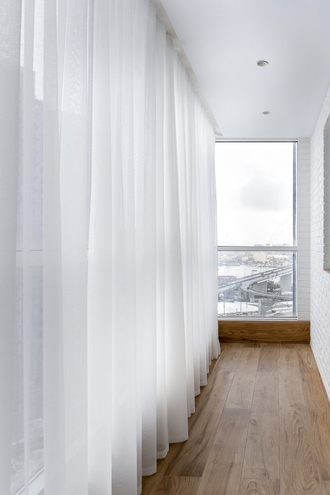 Источник вдохновения для домашнего уюта: балкон и лоджия среднего размера в стиле неоклассика (современная классика) с перегородкой для приватности и стеклянными перилами без защиты от солнца
