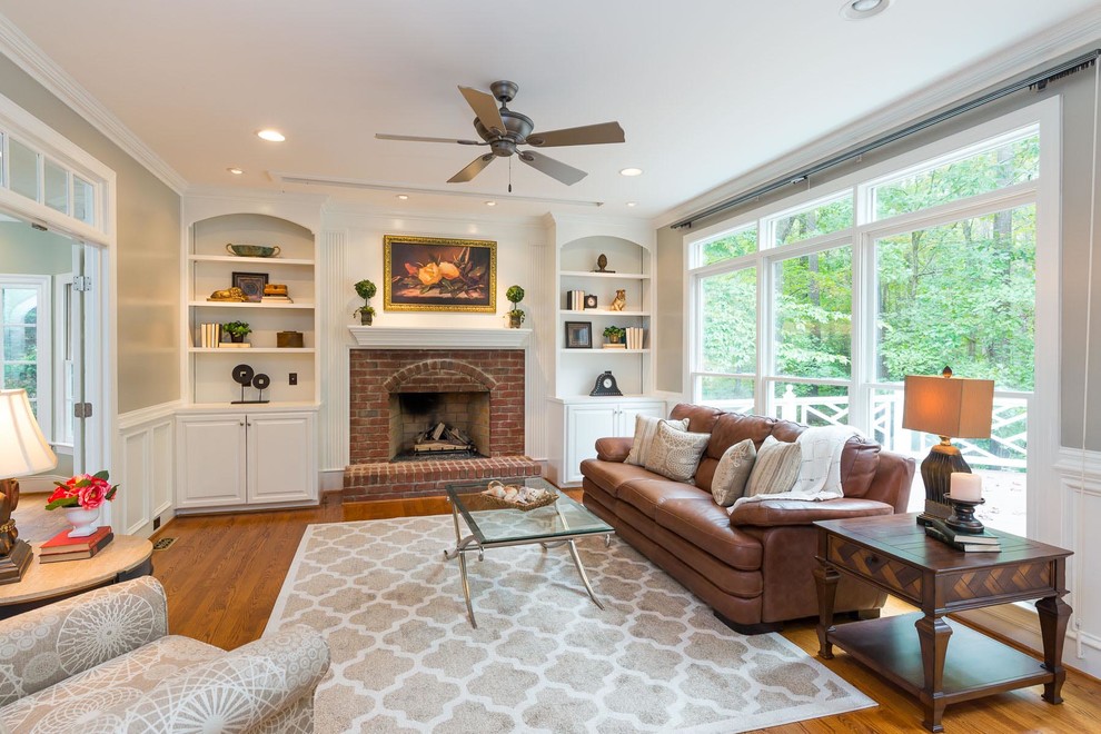 Mid-sized transitional enclosed family room in Raleigh with grey walls, medium hardwood floors, a standard fireplace, a brick fireplace surround, no tv and brown floor.