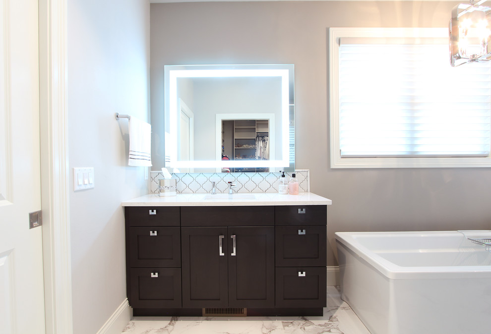 Design ideas for a large transitional master bathroom in Other with recessed-panel cabinets, brown cabinets, a freestanding tub, an alcove shower, a two-piece toilet, white tile, porcelain tile, grey walls, marble floors, an undermount sink, engineered quartz benchtops, white floor, a hinged shower door and white benchtops.