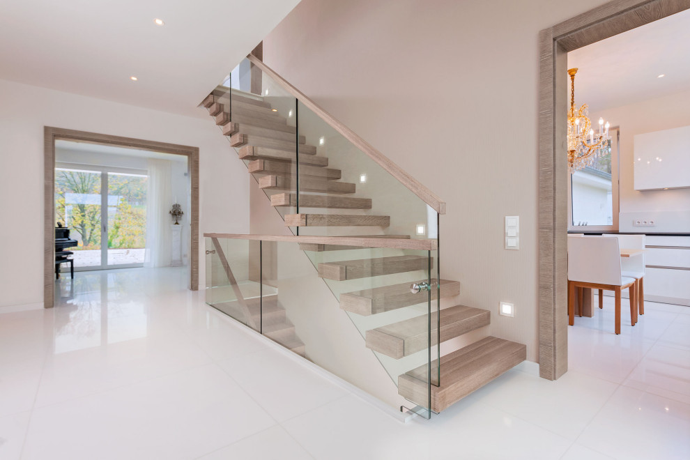 На фото: прямая лестница в современном стиле с деревянными ступенями и стеклянными перилами без подступенок с