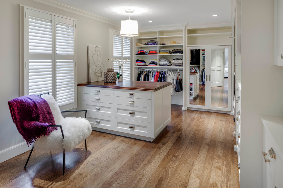 This is an example of a large transitional gender-neutral dressing room in Boston with flat-panel cabinets, white cabinets, medium hardwood floors and brown floor.