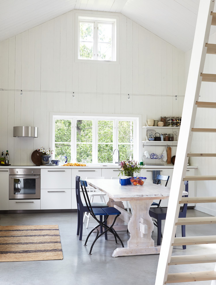 Expansive scandinavian kitchen/dining combo in Stockholm with concrete floors and white walls.