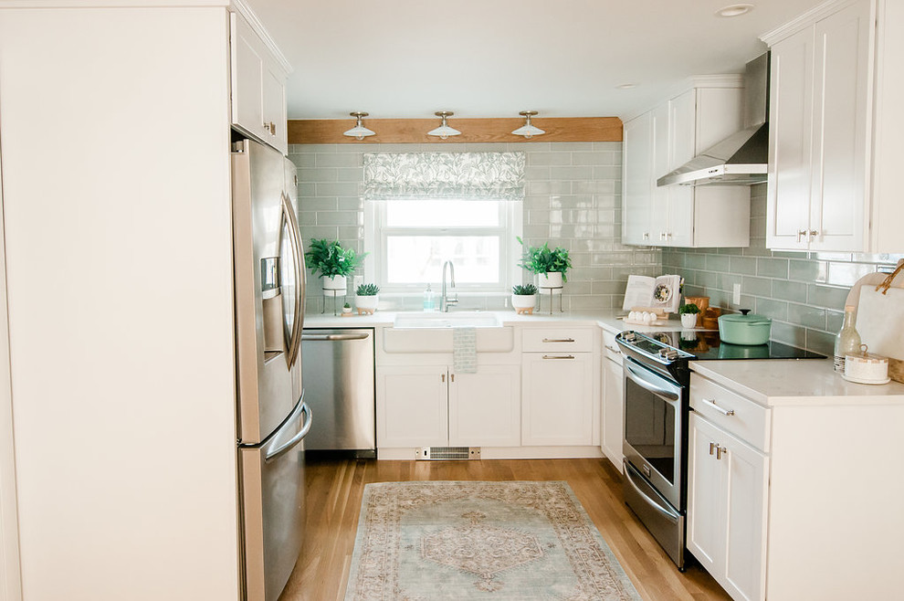 This is an example of a small country u-shaped eat-in kitchen in Boston with a farmhouse sink, shaker cabinets, white cabinets, stainless steel appliances, no island and white benchtop.