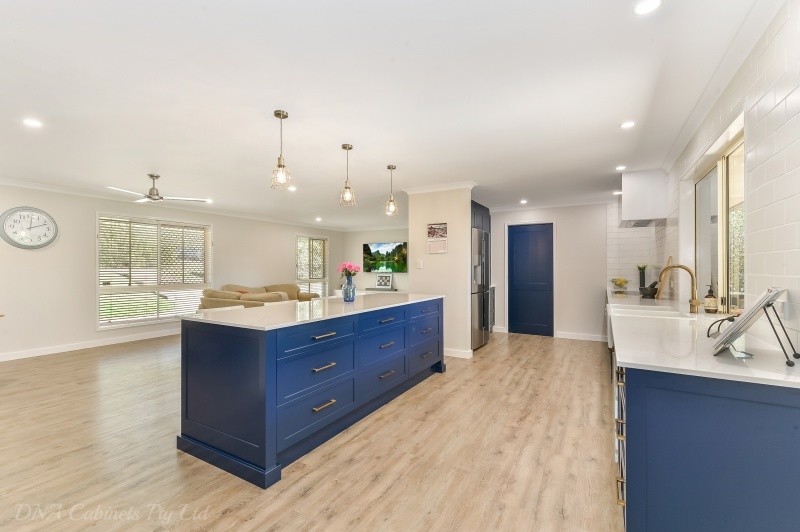 This is an example of a transitional galley eat-in kitchen with a double-bowl sink, blue cabinets, with island and stainless steel appliances.