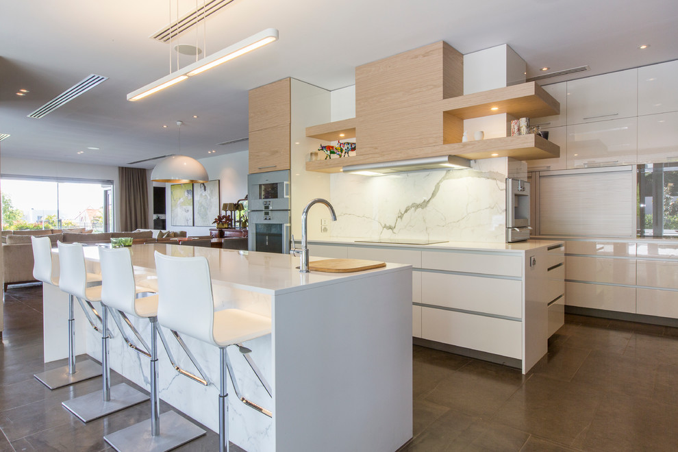 This is an example of a contemporary galley eat-in kitchen in Perth with with island, flat-panel cabinets, white cabinets, white splashback, stone slab splashback and stainless steel appliances.