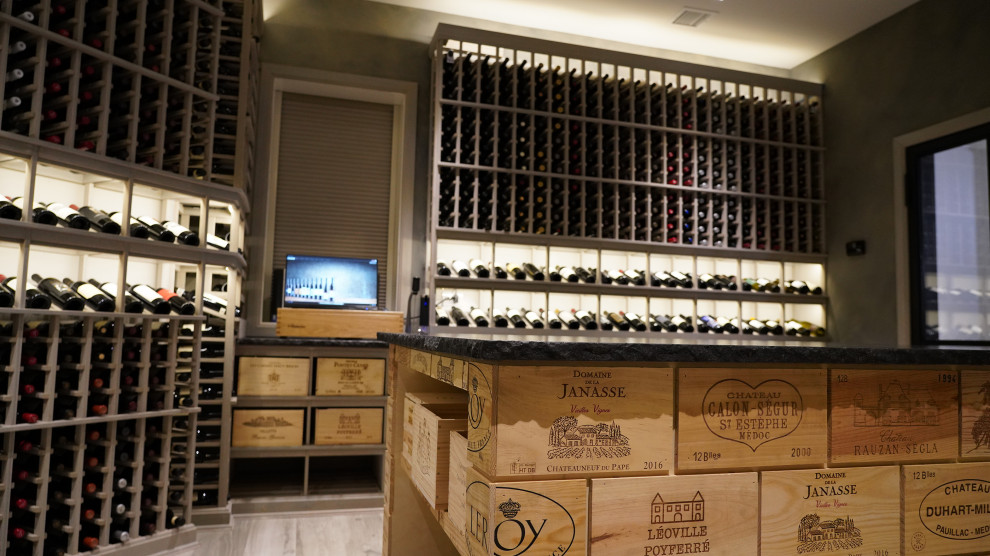 Expansive contemporary wine cellar in New York with light hardwood floors, display racks and grey floor.