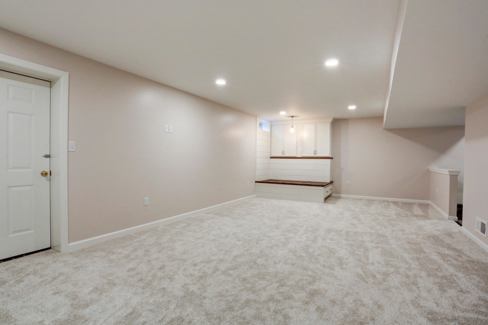 Modelo de sótano con ventanas de estilo americano grande con paredes beige, moqueta y suelo blanco
