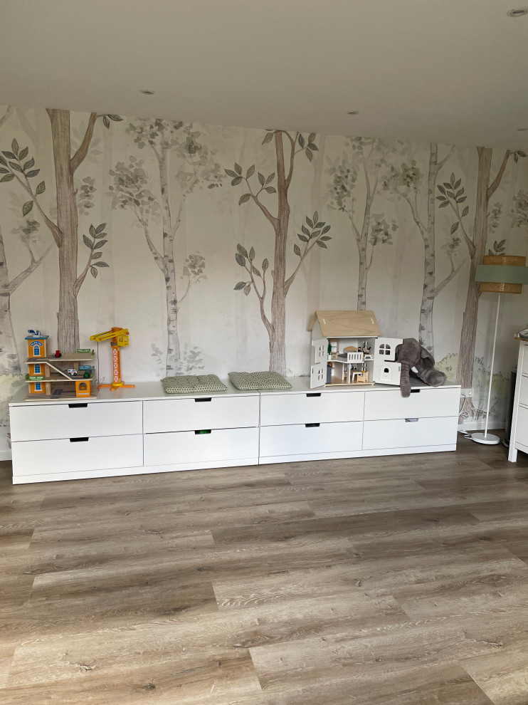 Ejemplo de habitación de bebé neutra de estilo de casa de campo grande con paredes beige, suelo vinílico, suelo marrón, bandeja y papel pintado