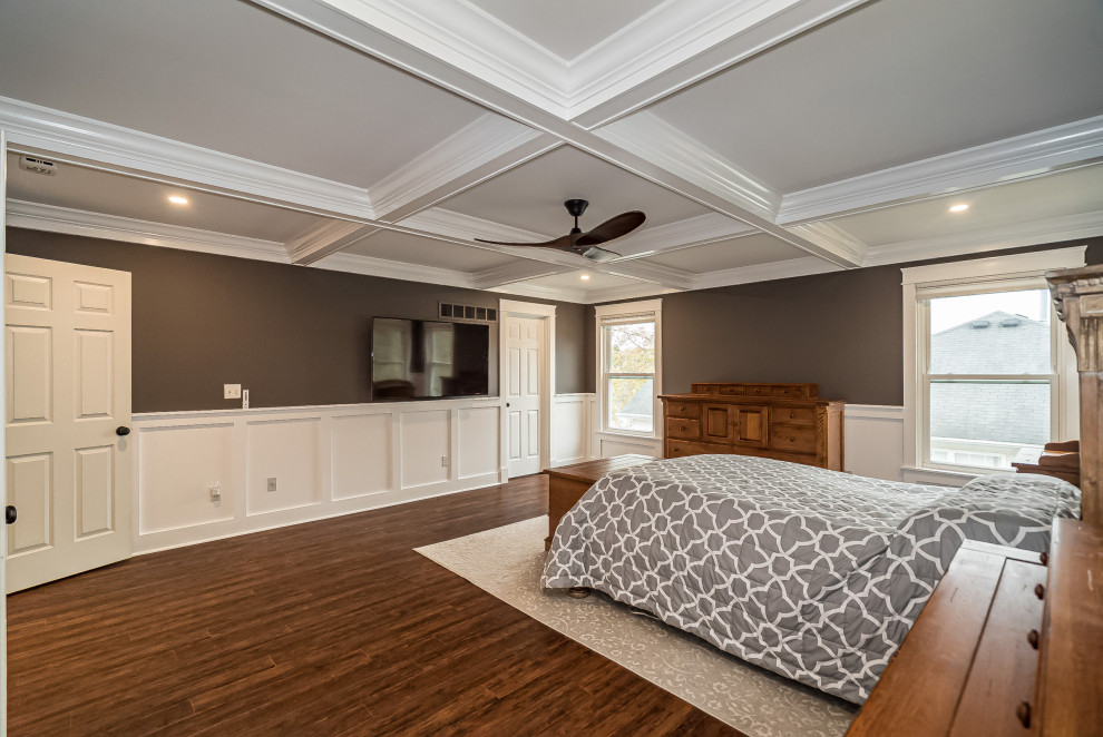 Ejemplo de dormitorio principal tradicional renovado grande sin chimenea con paredes marrones, suelo de madera en tonos medios, suelo marrón, casetón y boiserie